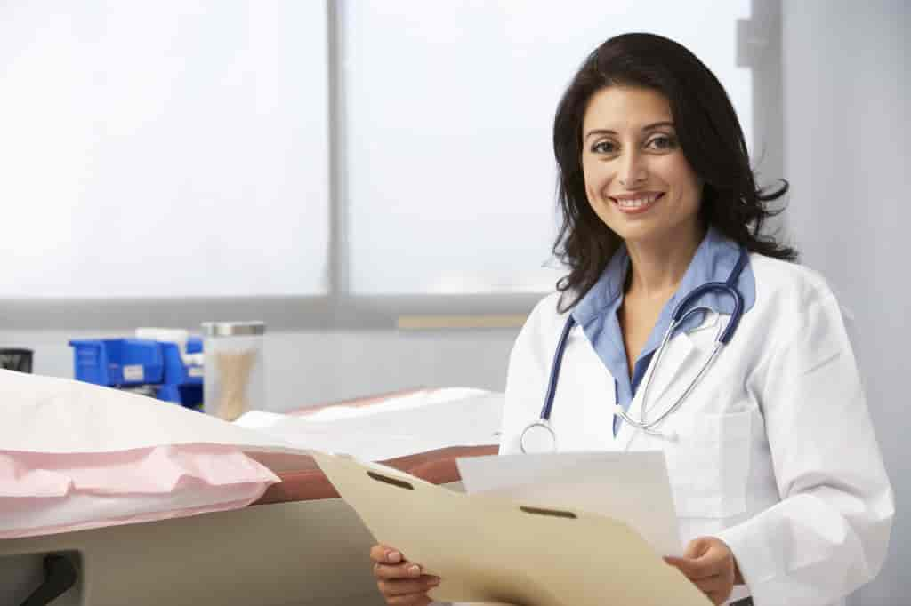 Female Doctor In Surgery Reading Patient Notes